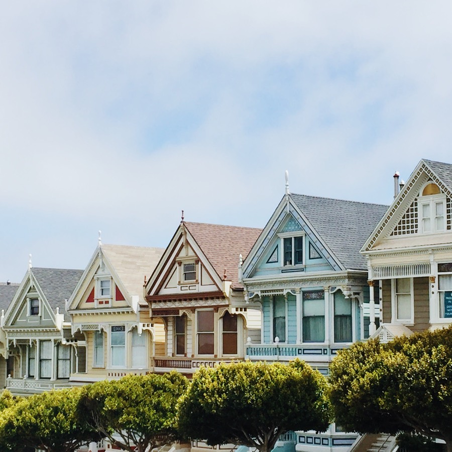 A terrace of painted Victorian houses behind clipped hedges