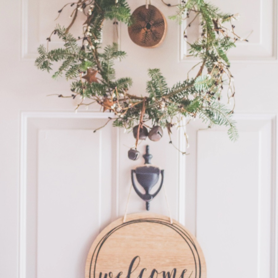 A wreath and a wooden welcome sign hanging on a front door