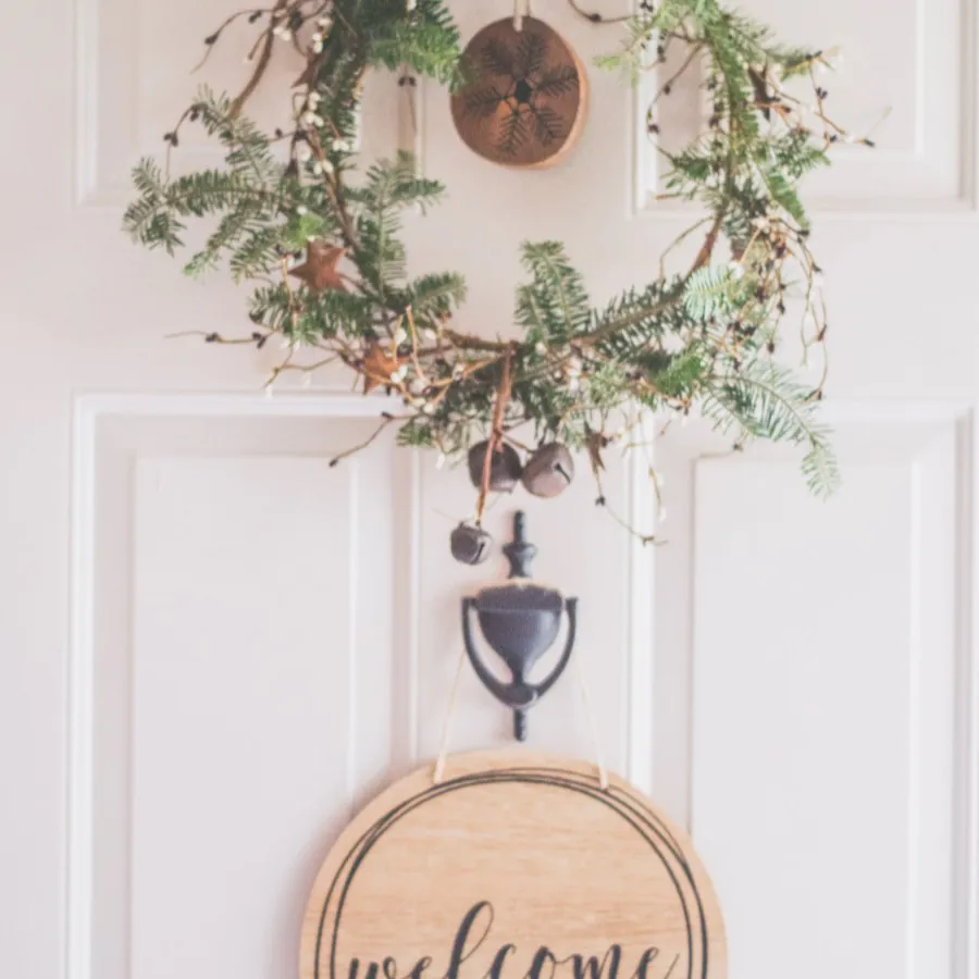 A wreath and a wooden welcome sign hanging on a front door
